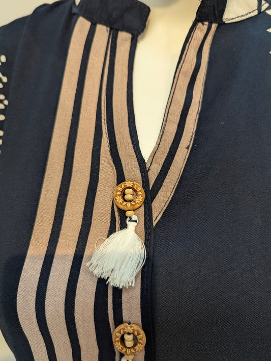 Navy blue garment with beige stripes and decorative elements on a mannequin.