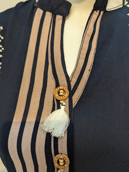 Navy blue garment with beige stripes and decorative elements on a mannequin.