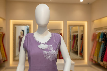 Mannequin wearing a purple dress with white embellishments in a store setting.